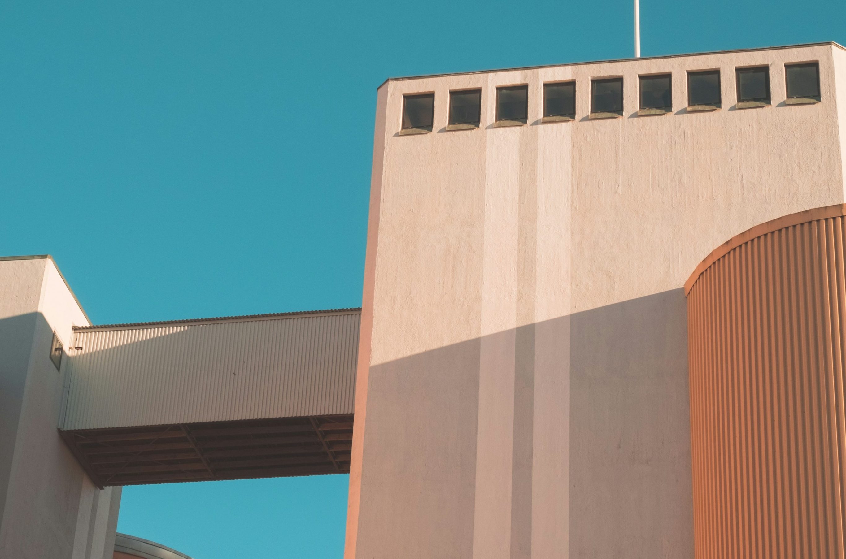 Gebäude vor blauem Himmel; Quelle: Strato hp-Baukasten Moderne Architektur mit hellen Farben und geometrischen Formen vor blauem Himmel.