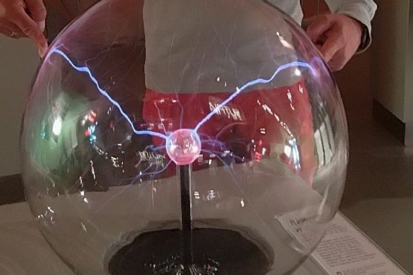 Blitze in der Plasmakugel; Quelle: Astrid Anders Glaskugel mit leuchtendem Plasma und elektrischen Entladungen in der Mitte.
